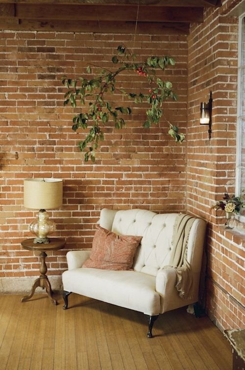 neutral loveseat at the corner of the brick wall